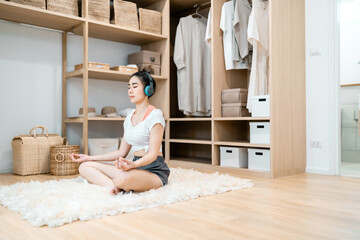 beautiful woman calm meditating wearing headphones in dressing room. spiritual gorgeous woman sitting listening to music control breathing. beautiful woman meditating listening to a song doing yoga