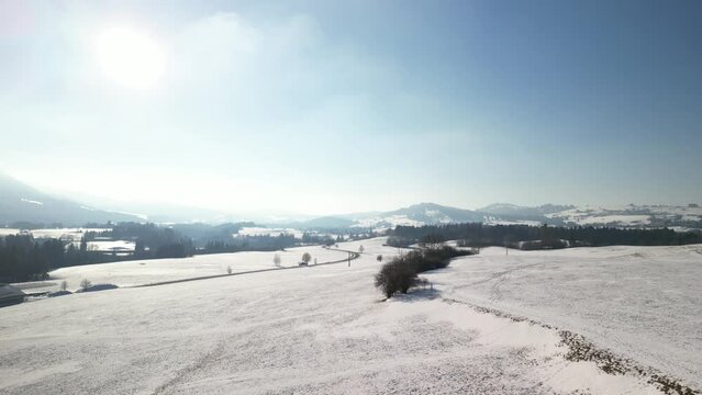 hills covered with snow show the surroundings of the city of nesselwang in the south of bavaria in germany and in the background you can see the alps which are also covered with snow shot with a drone