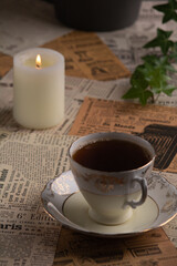 photo on newspaper clippings there is a cup of coffee next to a burning candle