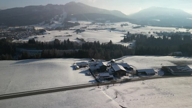 detached houses in the vicinity of the bavarian town of nesselwang in the south of bavaria near the alps filmed with a drone in winter with snow-covered mountains and bright sunshine
