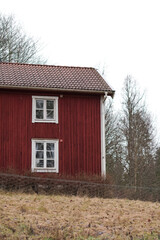 Obraz premium Typical red wooden house in foggy weather at the end of Winter in the countryside area of Sweden