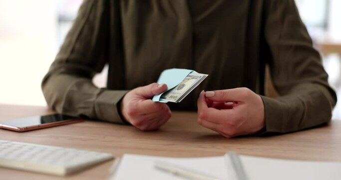 Woman hands count cash dollar money in envelope at workplace