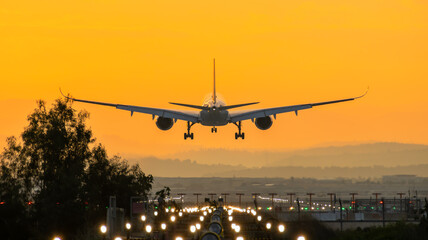 Naklejka na ściany i meble Airbus A350 landing into the sunrise