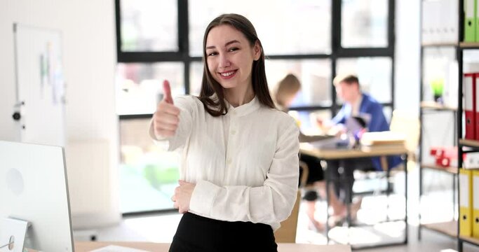 Beautiful smiling business woman showing thumb up gesture in office