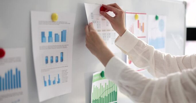 Hand of manager or teacher mentor pins on board of statistical report document