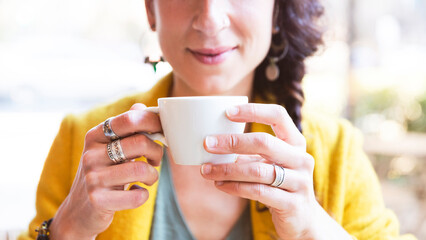 Unrecognizable woman holds a cup of tea in the foreground
