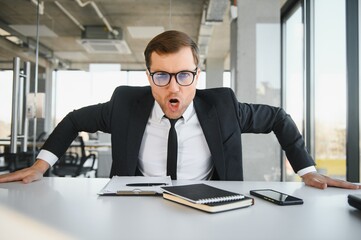 Angry businessman sitting at the table and screaming.