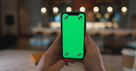 Hand holding a smartphone with green chroma key mock up screen. Device with mock-up display - technology, communication template