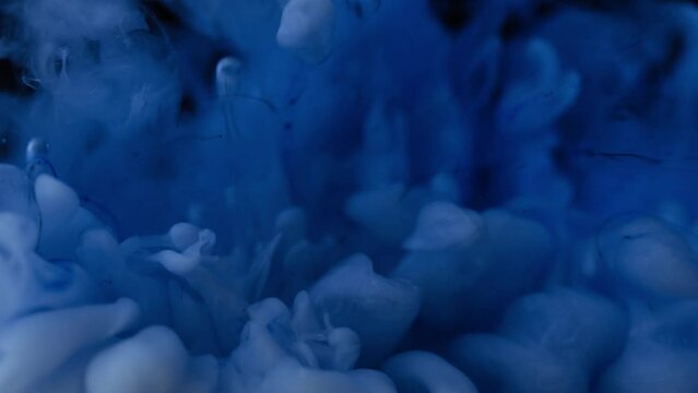 Blue color ink exploding in water over black background. Cloud ink swirling underwater. Abstract ink smoke explosion wallpaper.