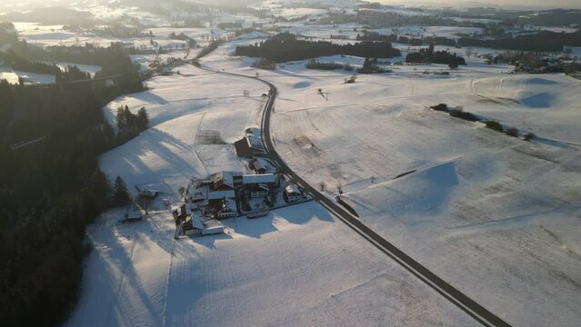 detached houses in the vicinity of the bavarian town of nesselwang in the south of bavaria near the alps filmed with a drone in winter with snow-covered mountains and bright sunshine
