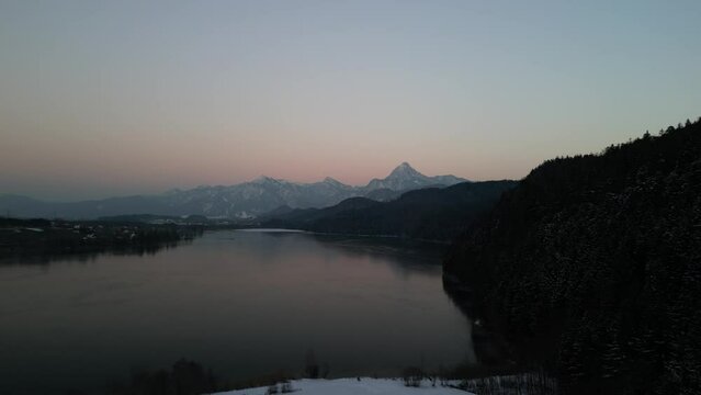 the Wei&szlig;ensee in the south of Bavaria with mountains covered with snow in the background filmed during the sunset with a drone and the lake in the foreground