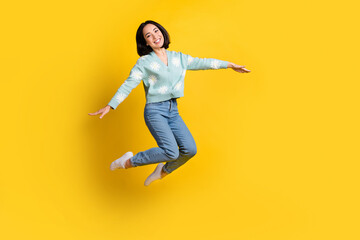 Fototapeta na wymiar Full size photo of cute good mood active woman bob hairstyle dressed blue pullover flying arms wings isolated on yellow color background