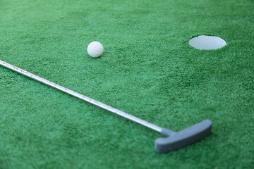 Mini golf equipment, golf club, ball and hole on green ground 