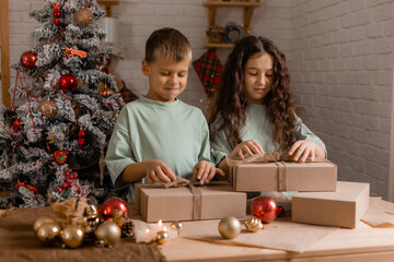 Naklejka premium boy and a girl are sorting Christmas gifts packed in craft paper