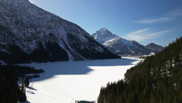 the plansee in the mountains with slightly snowy mountains and bright sunshine in austria near the city of reutte taken in winter