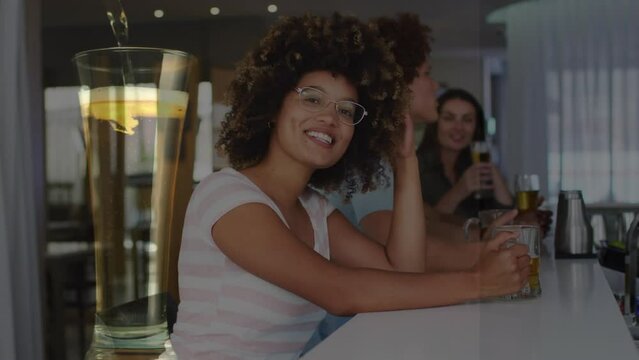 Animation of glass with beer over diverse friends having drink in bar