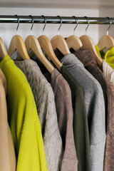 The basic wardrobe of a fashion stylist. Neutral colors: white, brown, beige, grey. Bright colors: yellow. White wardrobe, wooden hangers and towels