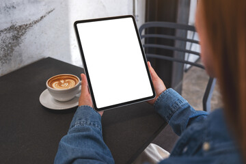 Mockup image of a woman holding digital tablet with blank white desktop screen in cafe