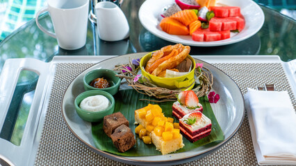 Tropical desserts, cakes, and fruits on a table set with plates.