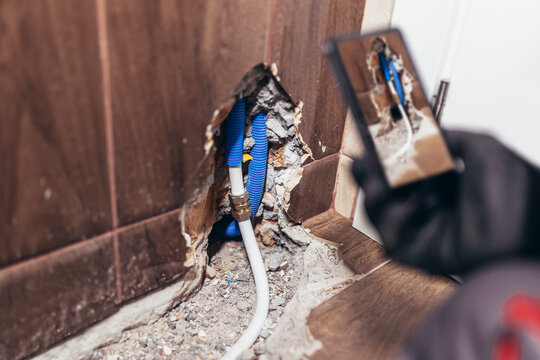 Handyman taking a photo of a damaged wall in the bathroom for insurance and verification purposes