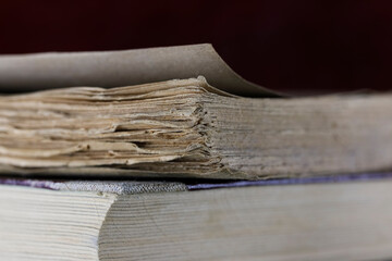 A badly worn old book is lying on top of another