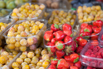 Trays of raspberries, strawberries and mirabelle plums on a market stall