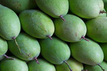 Stack of green mangoes for sale on a market stall
