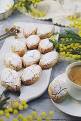 Ricciarelli,  gluten free almond cookies. Italian traditional cookies and cup of coffee. Fresh mimosa bouquet decoration - 571992714