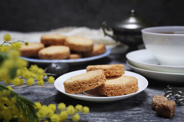 Palets bretons, french cookies. Shortbread Breton cookies, cup of tea and bouquet of mimosa - 571992774