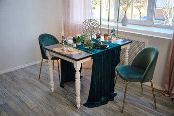 The luxury served table indoors in green colors. Dark wooden table, beautiful evening restaurant with luxury decor