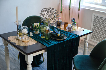 The luxury served table indoors in green colors. Dark wooden table, beautiful evening restaurant with luxury decor