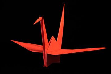 Red origami crane on black background