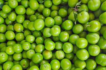 Stack of sour green plums on a market stall