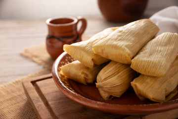 Tamales. Prehispanic dish typical of Mexico and some Latin American countries. Corn dough wrapped in corn leaves. The tamales are steamed. - 571993778