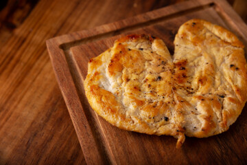 Pechuga asada. Homemade grilled chicken breast, flattened and seasoned. Rustic wooden table. Closeup image.