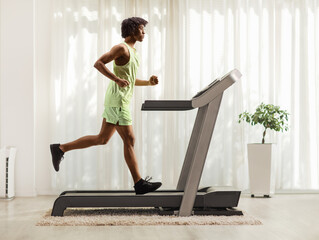 African american guy running on a treadmill at home