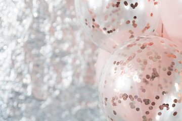 Pastel pink and transparent balloons on silver foil background