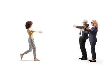 Full length profile shot of a young woman walking towards a mature man and woman with arms wide open