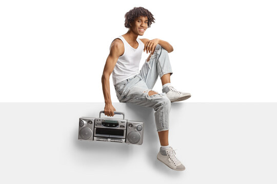 African american young man holding a boombox and sitting on a blank panel