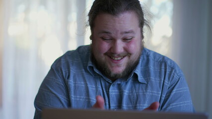 Young man winning something online. One happy fat casual person celebrates news in front of laptop computer feeling exciteement. Winner concept