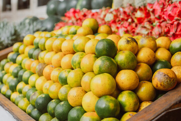 Tangerines are green, yellow and orange in a wooden box. Large selection of fresh citrus. A stylish concept of natural organic products.