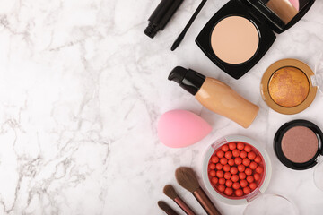 Beauty blender and foundation, bb cream or concealer, blush, eye shadow and other cosmetics on a...