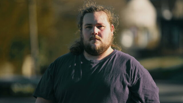 One Young Casual Man Standing Outdoors Looking At Camera Close Up Face With Serious Expression