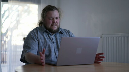 One sad man feeling despair in front of laptop computer. Unhappy emotion of a male fat person not liking result online feeling frstration
