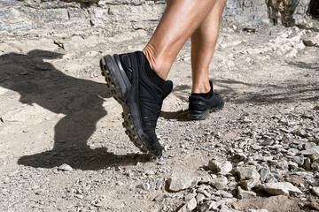 close up legs man in trekking shoes walking on stones trail