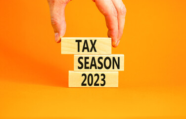 Tax season 2023 symbol. Concept words Tax season 2023 on wooden blocks on a beautiful orange table orange background. Businessman hand. Business Tax season 2023 concept. Copy space.