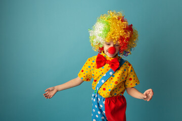 Funny kid clown against blue background. Happy child playing with festive decor. 1 April Fool's day concept
