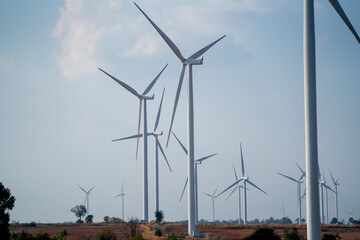 Windmill or wind turbine cluster in the field with blue sky for concept of geen energy to save...