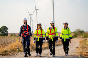 Group of engineer or technician man and woman walk along the road far from windmill or wind turbine after finish work.