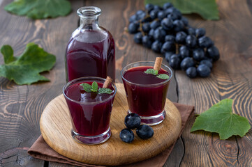 Homemade grape mors. A bottle and two glagges of fresh Black Grapes Juice with bunch of grapes on...